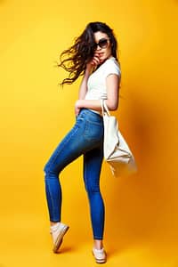 beautiful young woman sunglasses white shirt blue jeans posing with bag